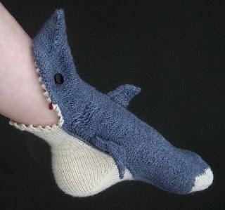 A photo of a foot wearing a sock shaped like a slipper. The appearance is that the shark sock is eating the foot!