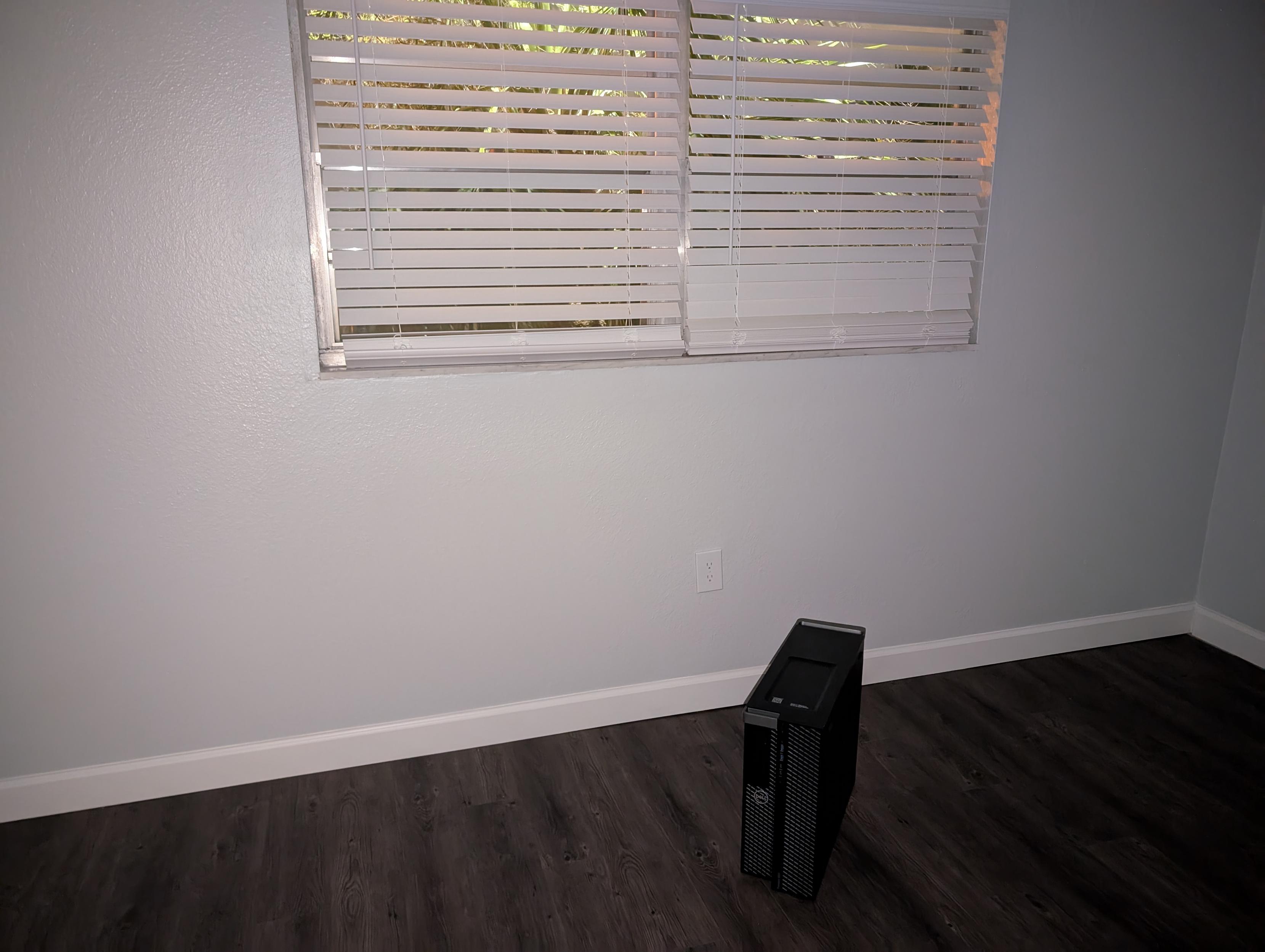 a dell computer tower in an empty room taken with flash