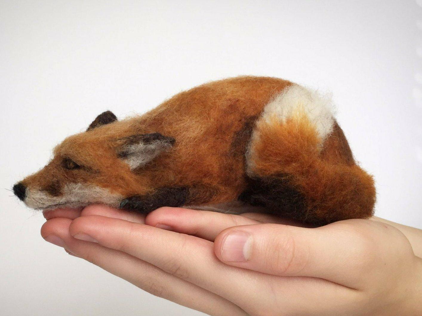 A photo of a small red fox made of felt. It's side on and fully occupies the artists hands