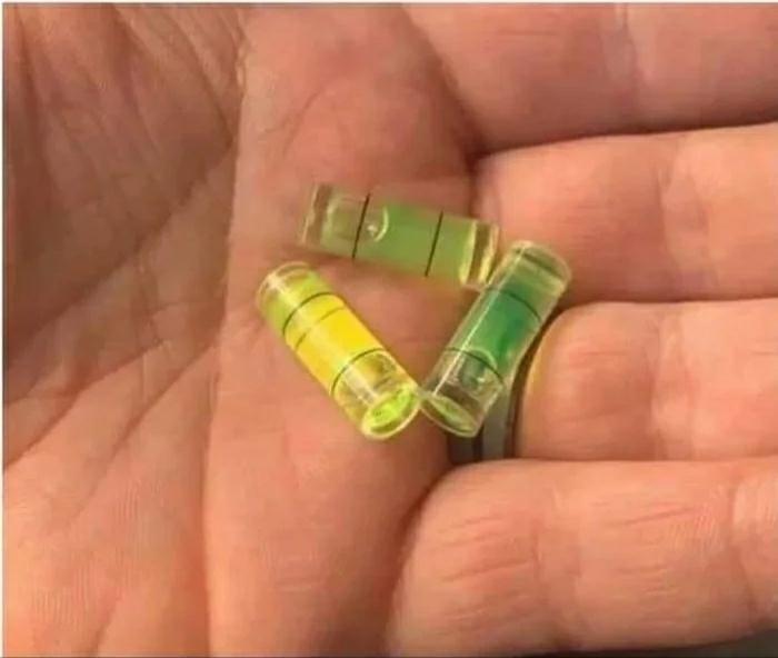Three spirit level vials, also known as bubble level vials, held in a person's hand.