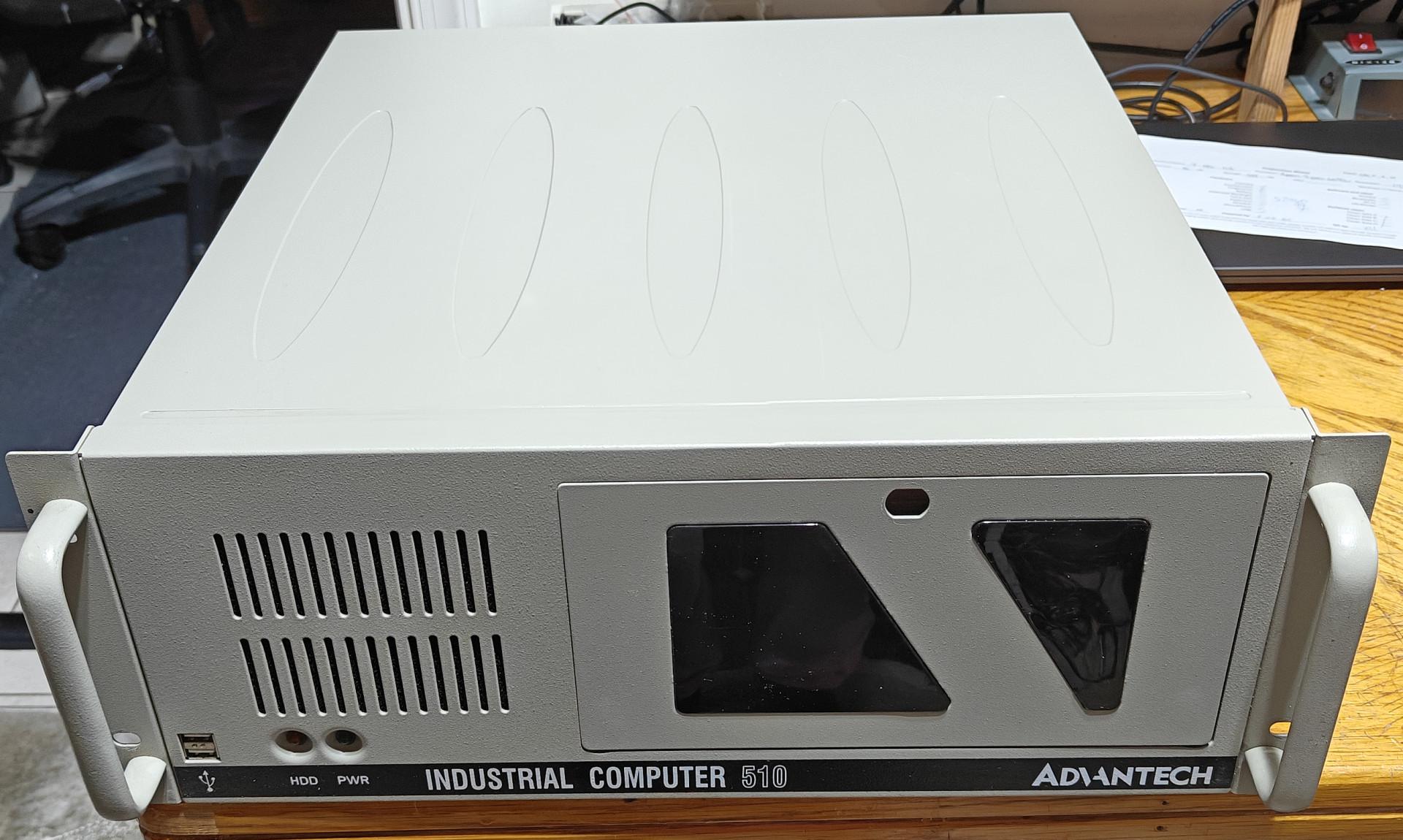 A front-angle photograph showcases a beige 4U rackmount computer case labeled "Industrial Computer 510" by Advantech. The rugged metal front panel is equipped with two heavy-duty vertical handles on the left and right edges for rack installation. The left section features a series of vertical ventilation slots above a single USB port, a hard drive indicator light, and a power light. The right side contains a large, flush-fitting lockable access door with two distinct angular dark transparent viewing windows, designed to protect internal drive bays while keeping indicator lights or displays visible.