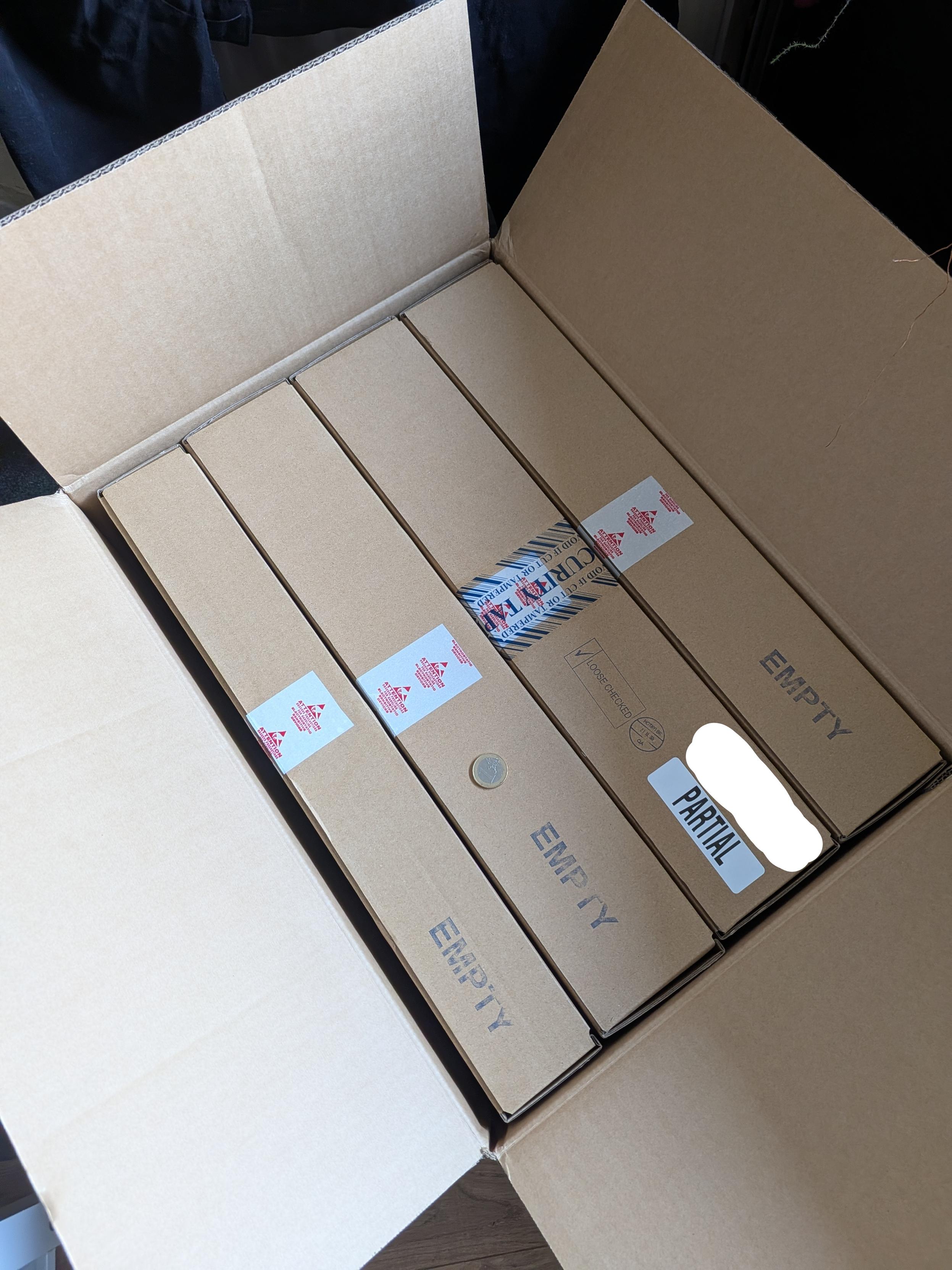 A very large box, about 0.5 m on its longest side, containing four smaller boxes. Three are marked 'empty', while one is labelled 'partial'. A one-Euro coin sits on top looking very small.