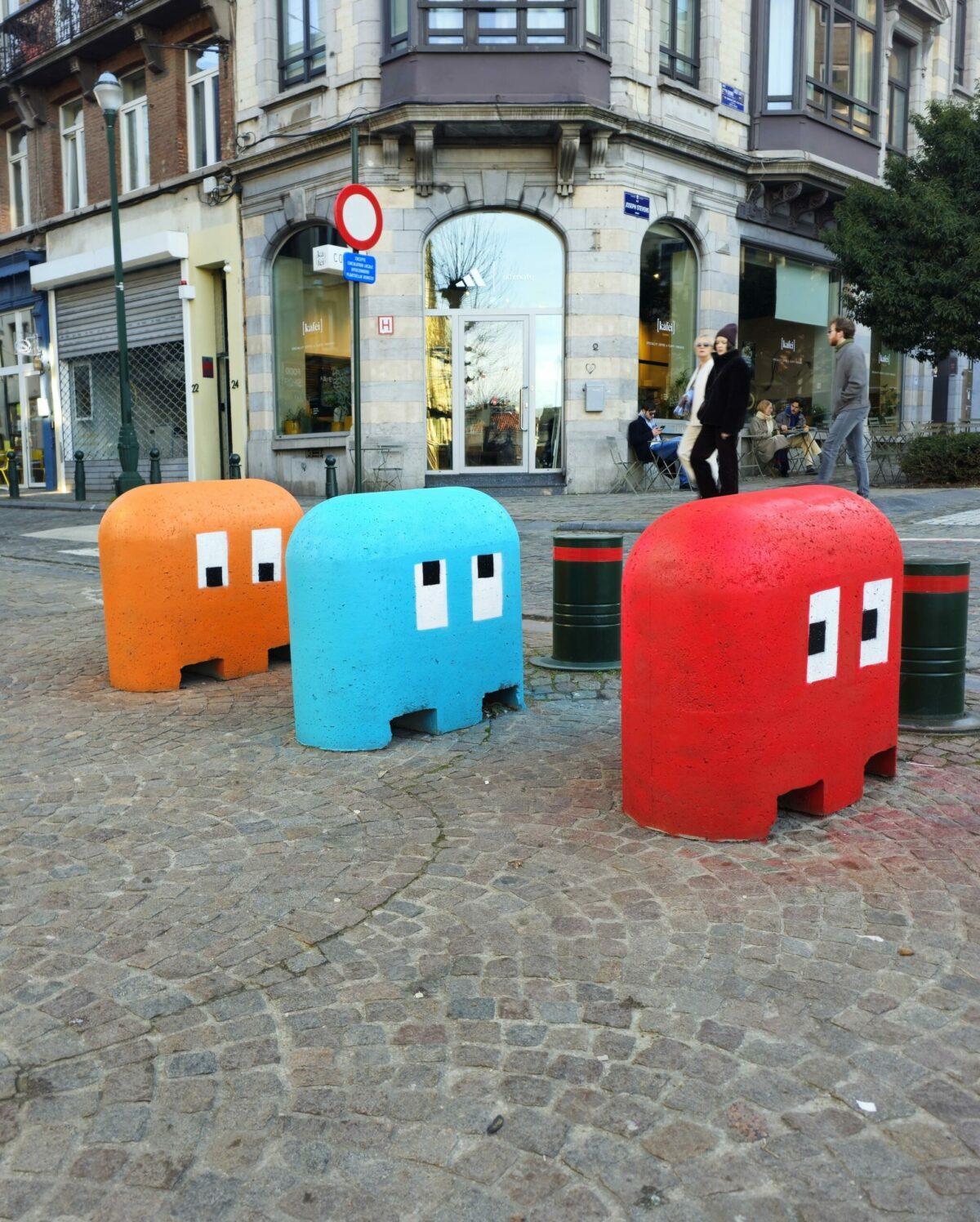 Concrete street bollards painted to look like the colorful ghosts (Blinky, Inky, and Clyde) from the classic arcade game Pac-Man